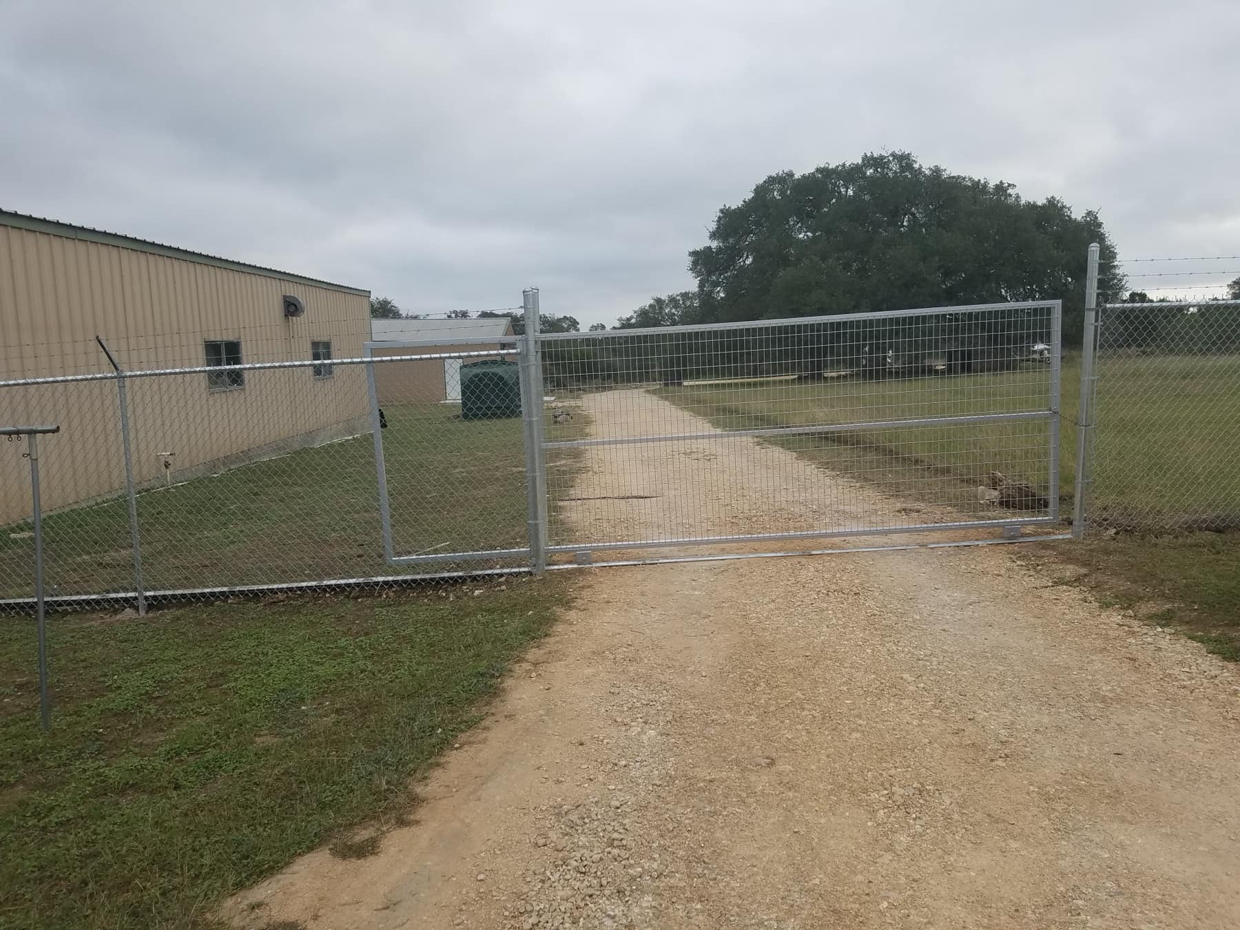 Galvanized chain-link slide gate across a gravel drive
